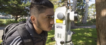 Male student looking through a total station